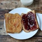 Peanut Butter and Jelly Sandwich with a heart carved into the peanut butte sitting on a plate.