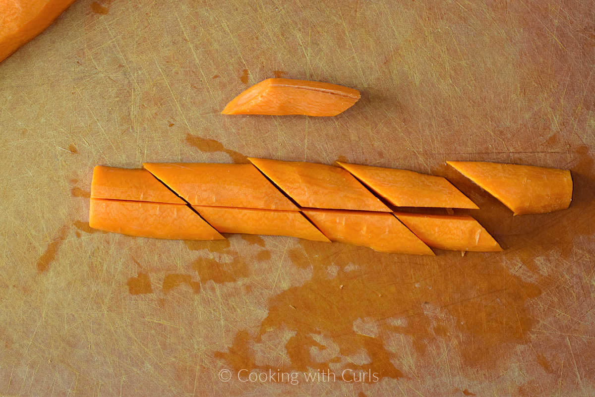 A carrot cut into pieces on a cutting board.