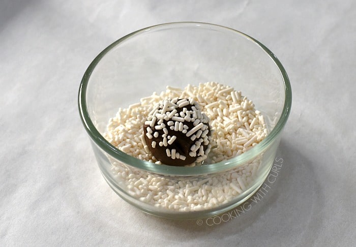Ball of cookie dough rolled in white sprinkles in a small bowl cookingwithcurls.com