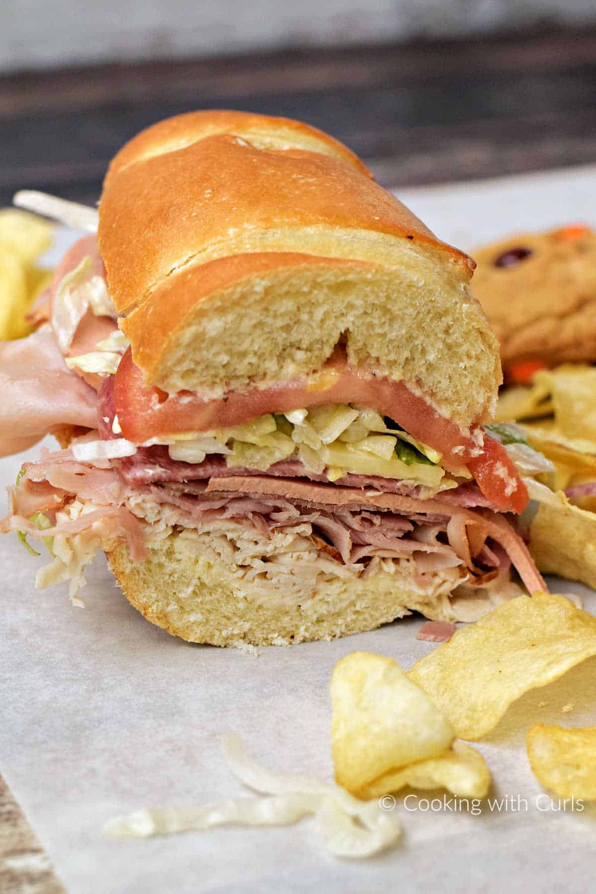 Half of a classic Italian sub sandwich surrounded by potato chips.