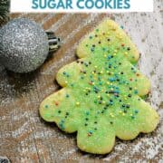A cut-out sugar cookie tree decorated with green sugar and colored sprinkles and title graphic across the top.