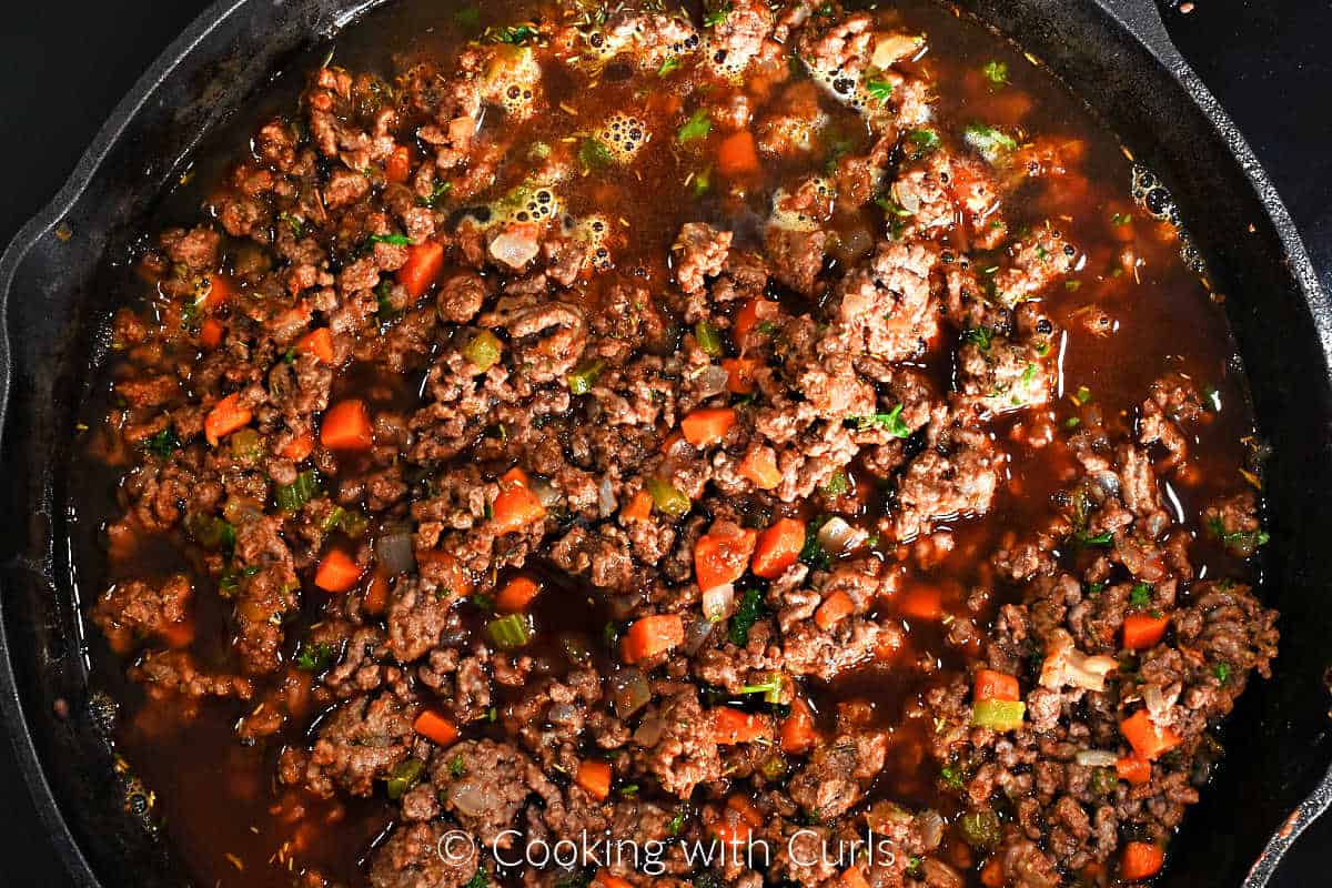 Ground beef, carrots, celery, onion, and beef stock in a cast iron skillet. 