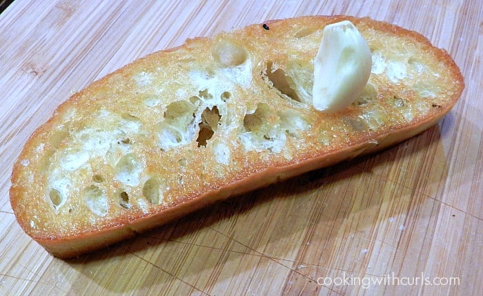 A garlic clove sitting on top of a slice of crostini.
