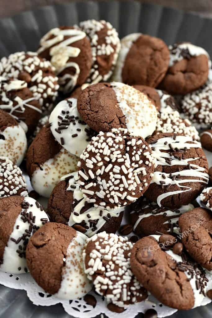White chocolate and jimmies coated mocha cookies piled on a metal plate.
