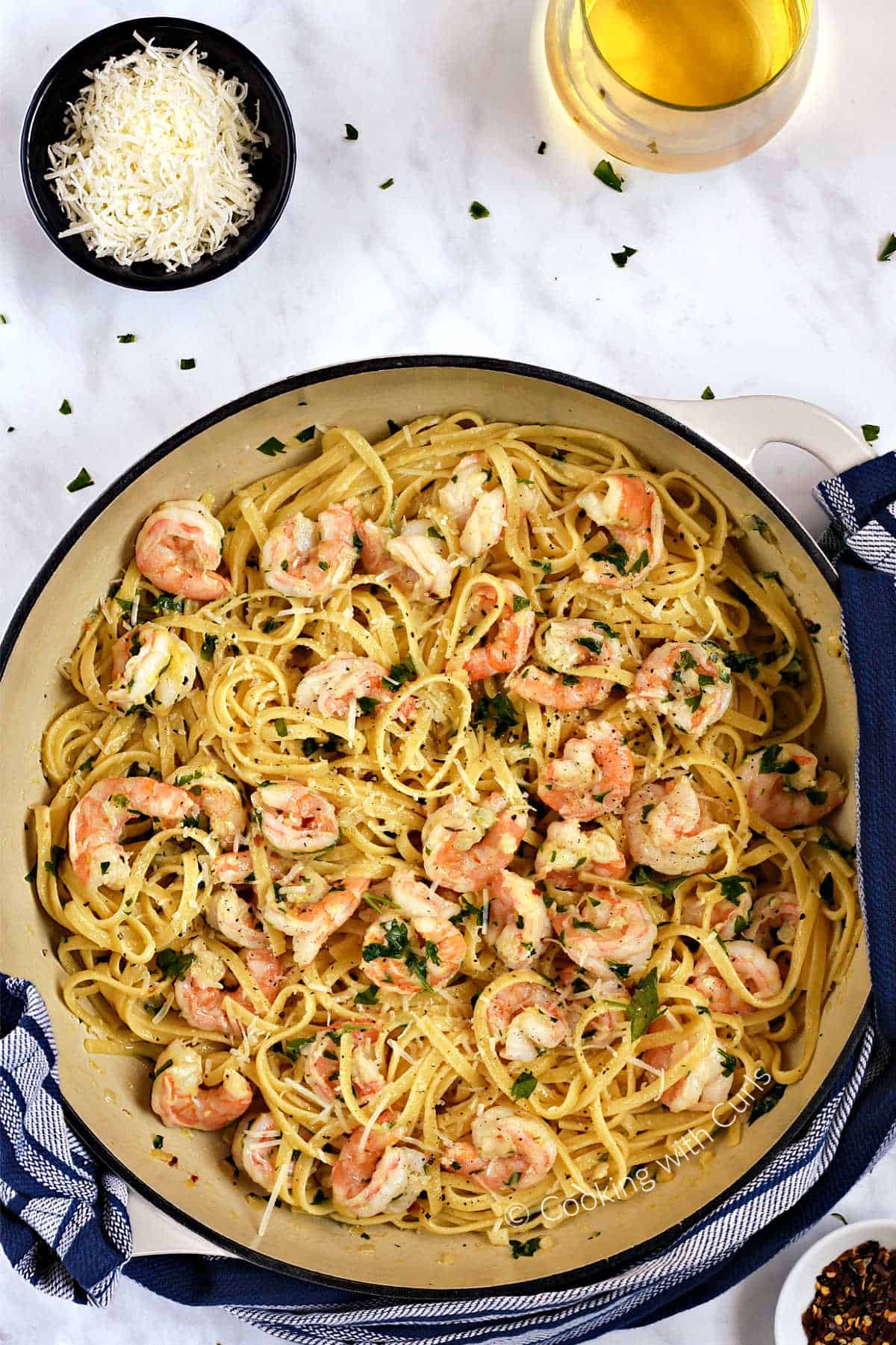 Looking down on shrimp and linguine pasta tossed with garlic, lemon, and wine sauce in a large skillet.