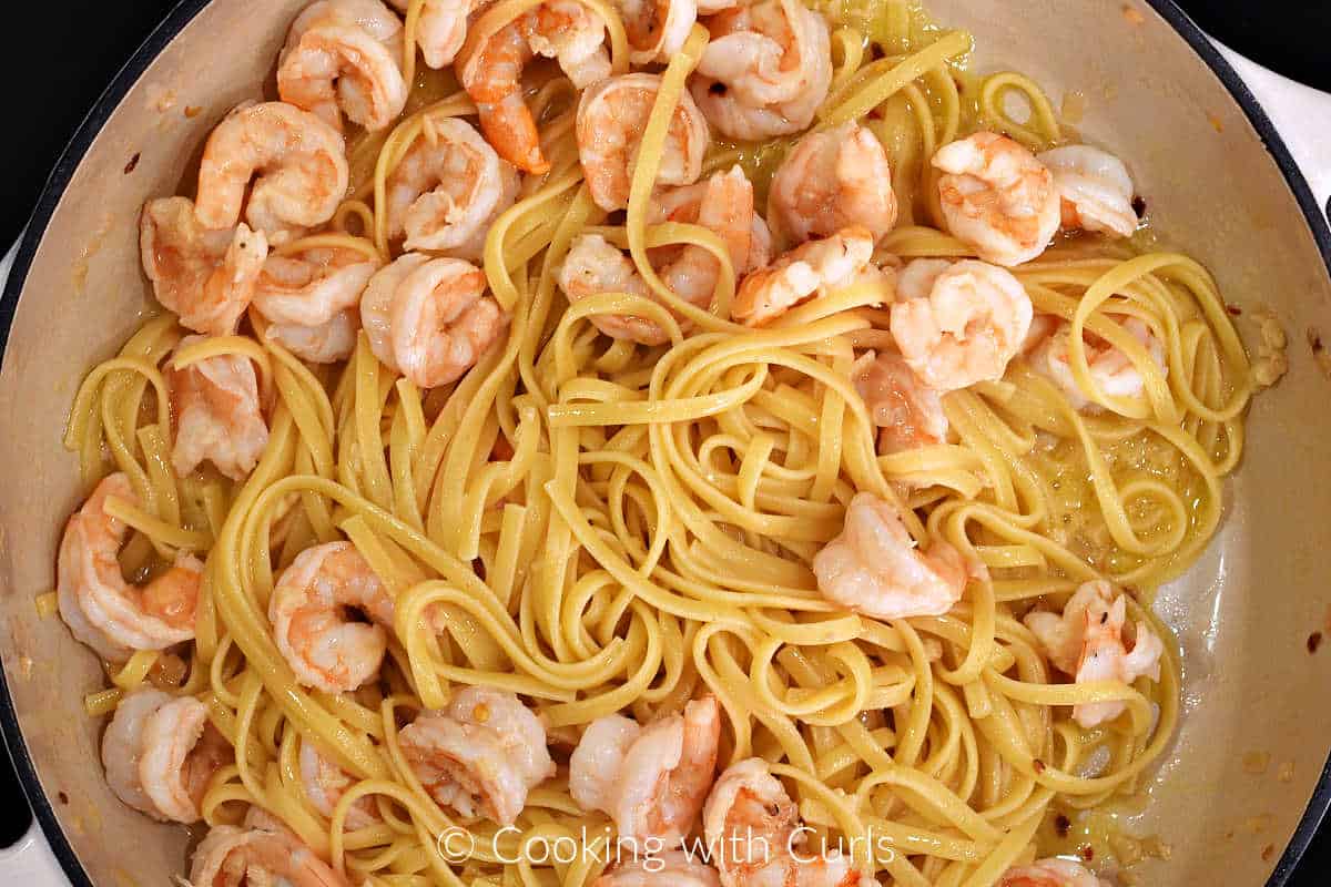 Shrimp and linguine mixed with the garlic lemon sauce in a large skillet.