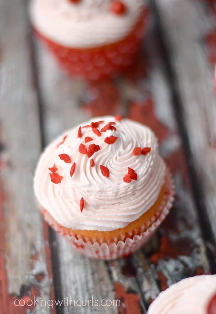 Cherry chip cupcakes decorated for Valentine's Day with red lip sprinkles on top of the pale pink frosting.