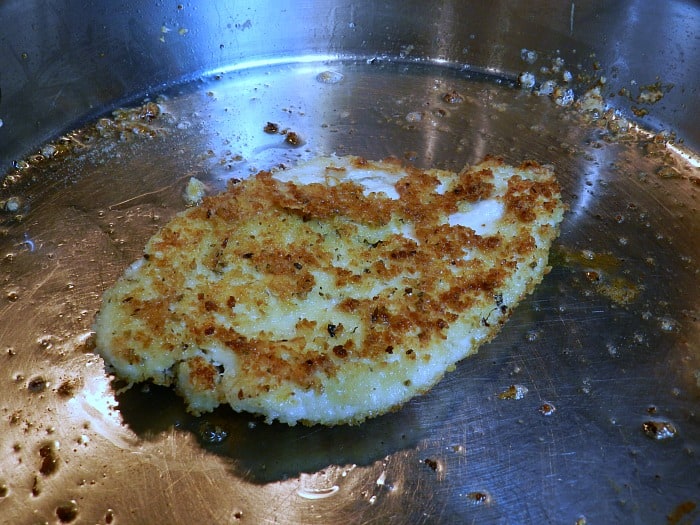 A pan-fried panko crusted chicken breast in a skillet.