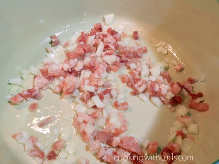 Chopped pancetta and onions in oil cooking in a large pot.