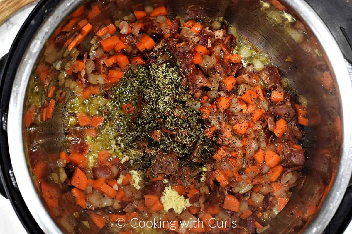 Minced garlic, dried thyme and rosemary added to sautéed vegetables in a pressure cooker. 