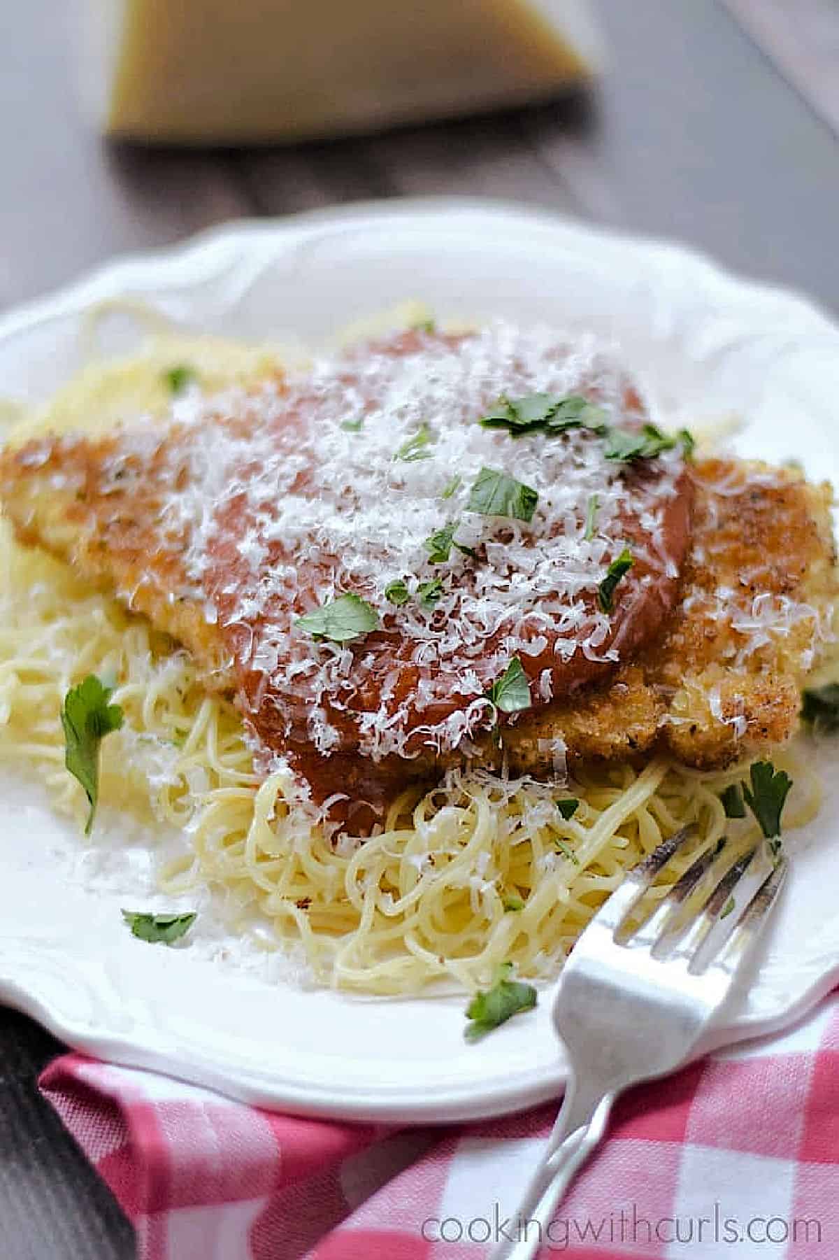 Crispy panko crusted chicken parmesan on a bed of angel hair pasta and topped with marinara sauce and grated parmesan.