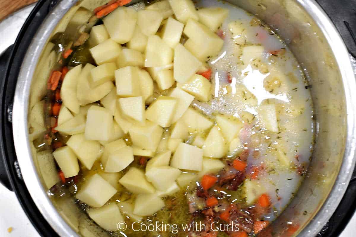 Potato chunks and clam juice added to the sautéed vegetables in a pressure cooker. 