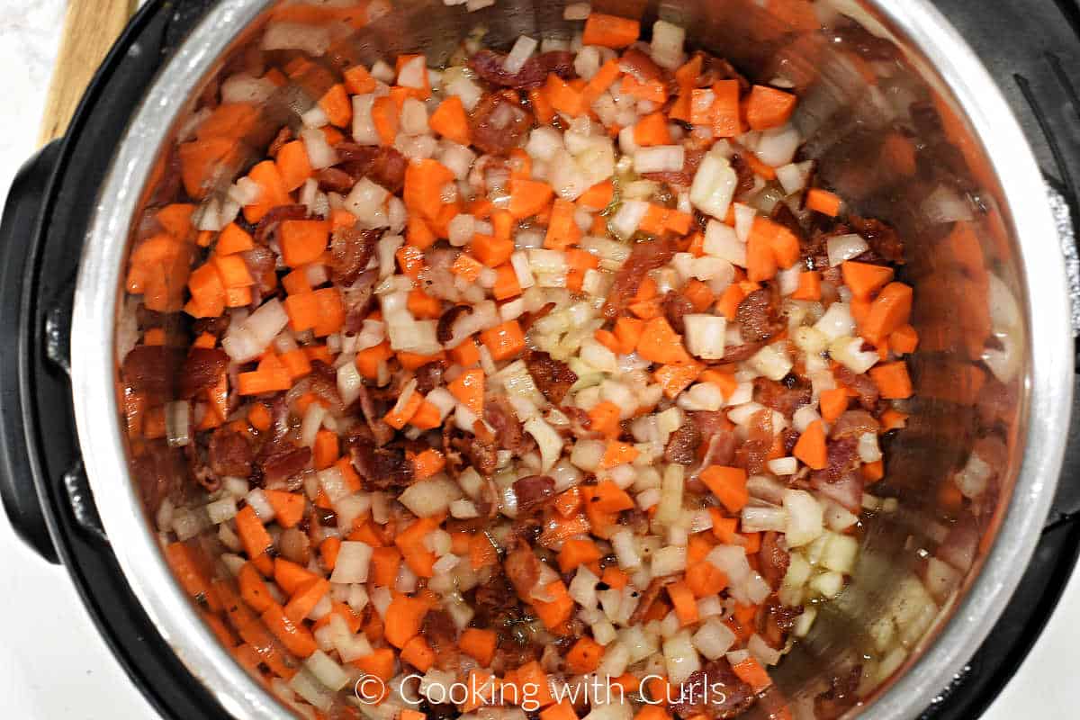 Sautéed bacon pieces, onion, and carrots in a pressure cooker. 
