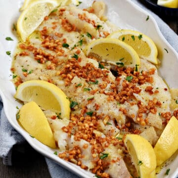 Sole with Caramelized Garlic and lemon wedges on a large platter.