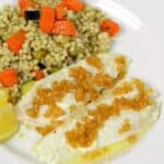 Sole topped with Caramelized Garlic on a white plate with couscous