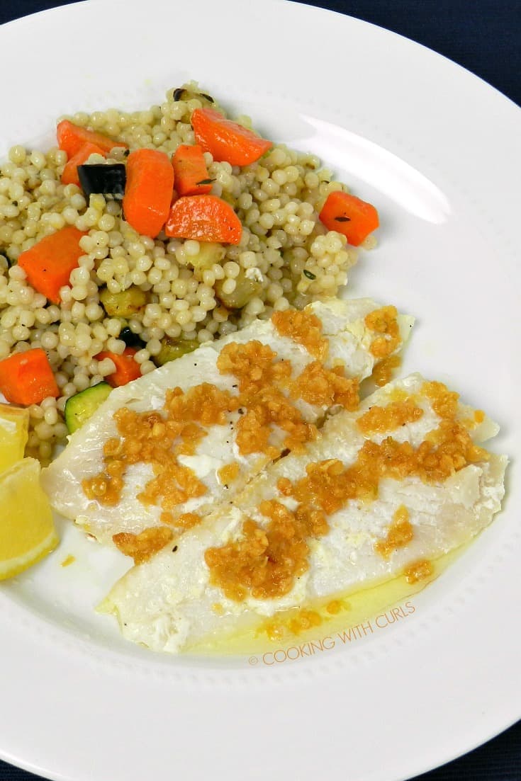Sole topped with Caramelized Garlic on a white plate with couscous
