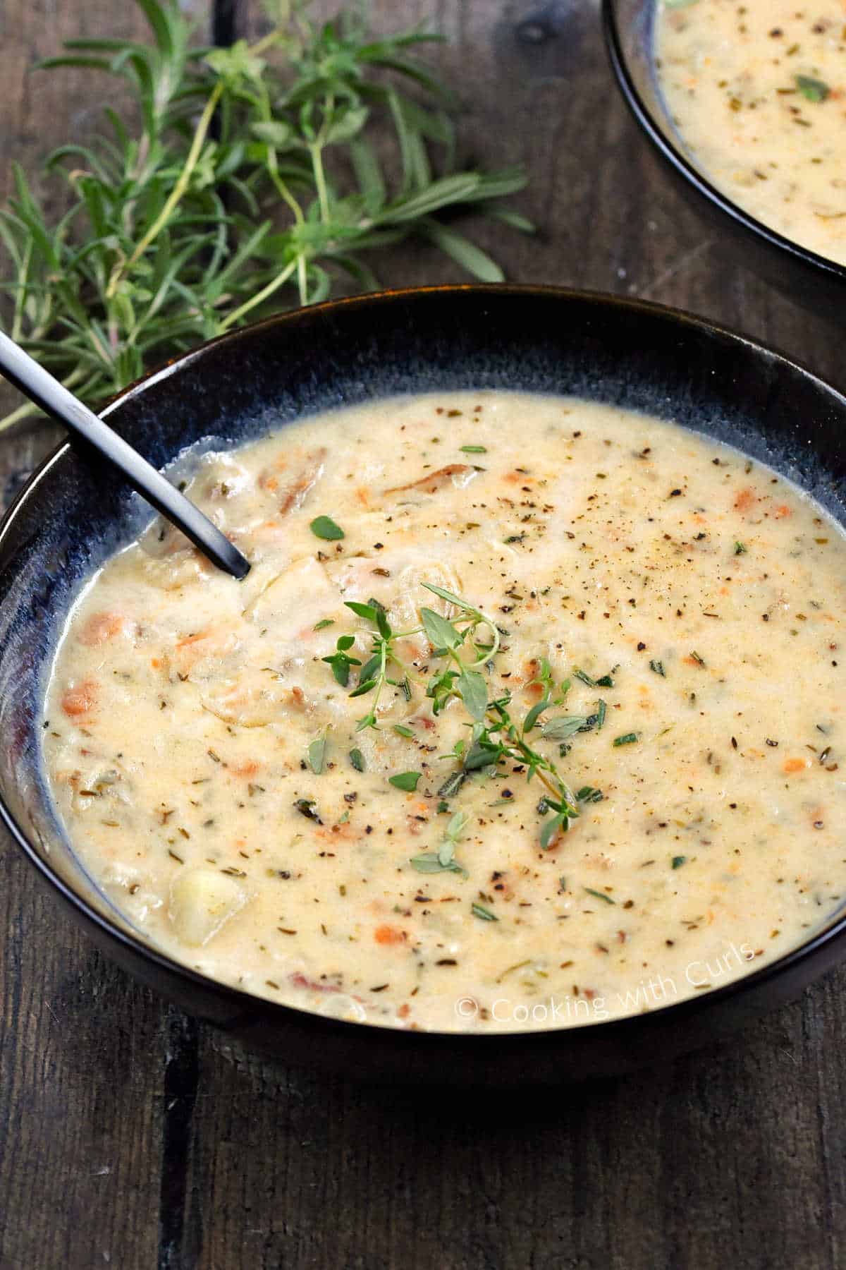 Two bowls of creamy Boston Clam Chowder topped with fresh thyme and rosemary. 