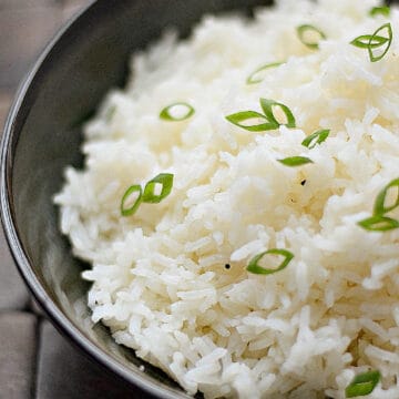 A bowl of steamed rice recipe with black pepper and sliced green onion on top.