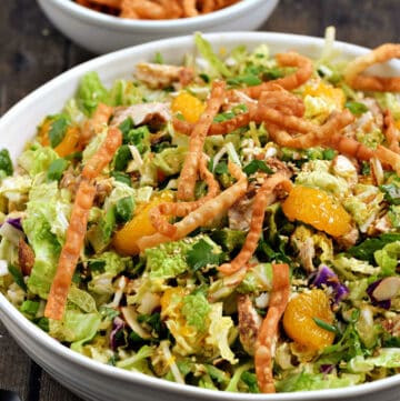 Chinese Chicken Salad topped with crispy wonton strips and mandarin orange segments in a large serving bowl.