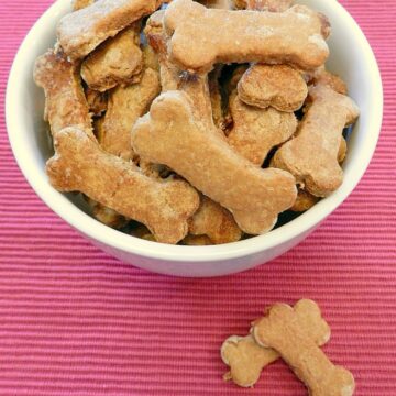 Homemade Peanut Butter and Banana Dog Biscuits in a bowl sitting on a pink placemat.