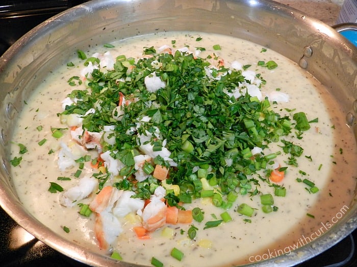 Lobster, vegetables, parsley and green onions added to the sauce in a large skillet. 