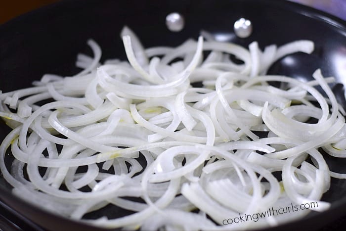 Thinly sliced onion in a skillet.