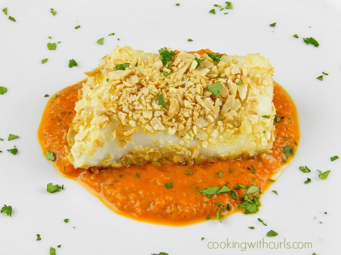 Tortilla Crusted Sea Bass with Roasted Red Pepper Puree served on a large white plate