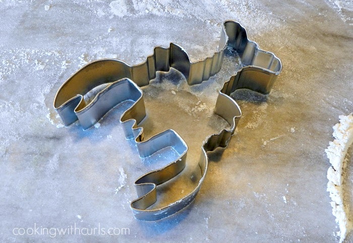 A metal Lobster cookie cutter sitting on a floured marble board. 