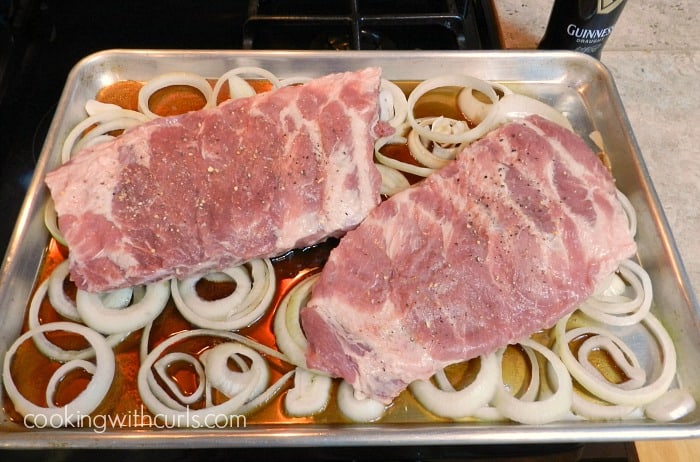 onion slices, beer and seasoned ribs in a baking pan 