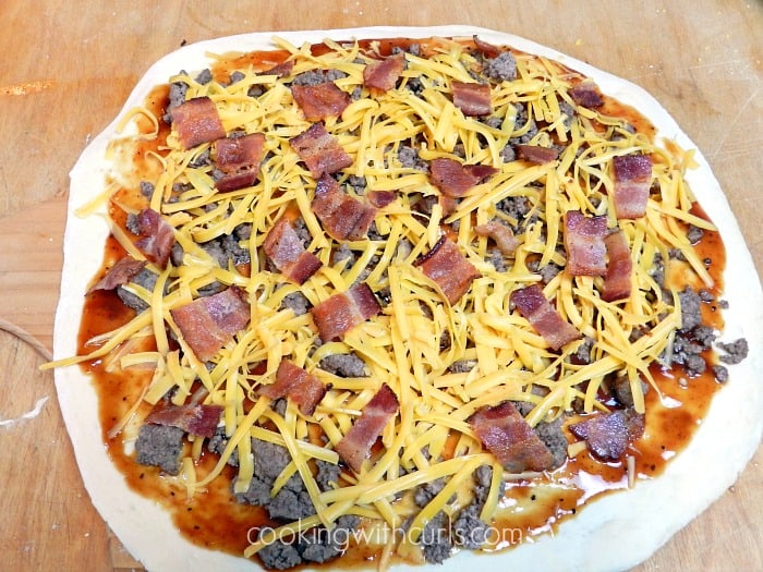 pizza dough with sauce, cheese, beef and bacon on top