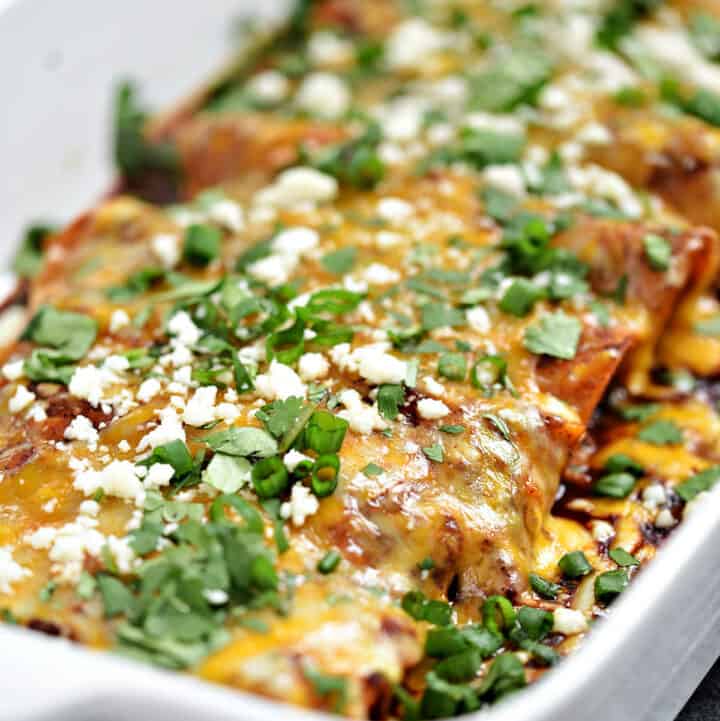 Chicken Enchiladas topped with red sauce and melted cheese in a baking dish.