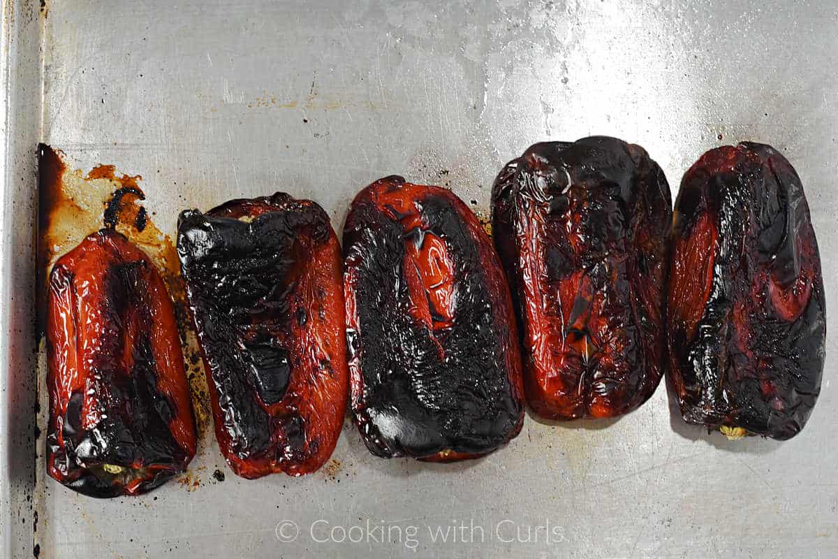 Five-charred-red-pepper-on-a-baking-sheet.