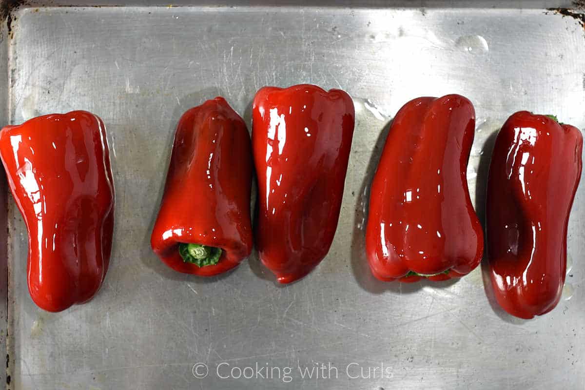 Five-red-peppers-rubbed-with-oil-on-a-baking-sheet.