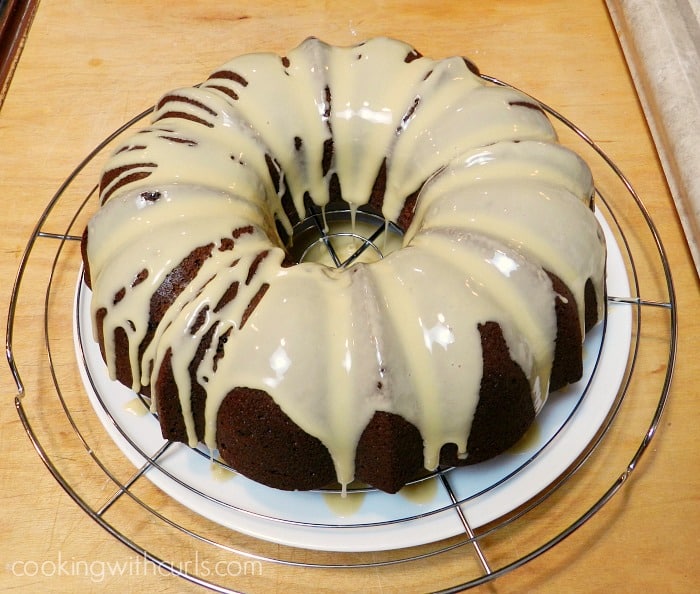 Pour glaze over cake sitting on a wire rack and large plate cookingwithcurls.com