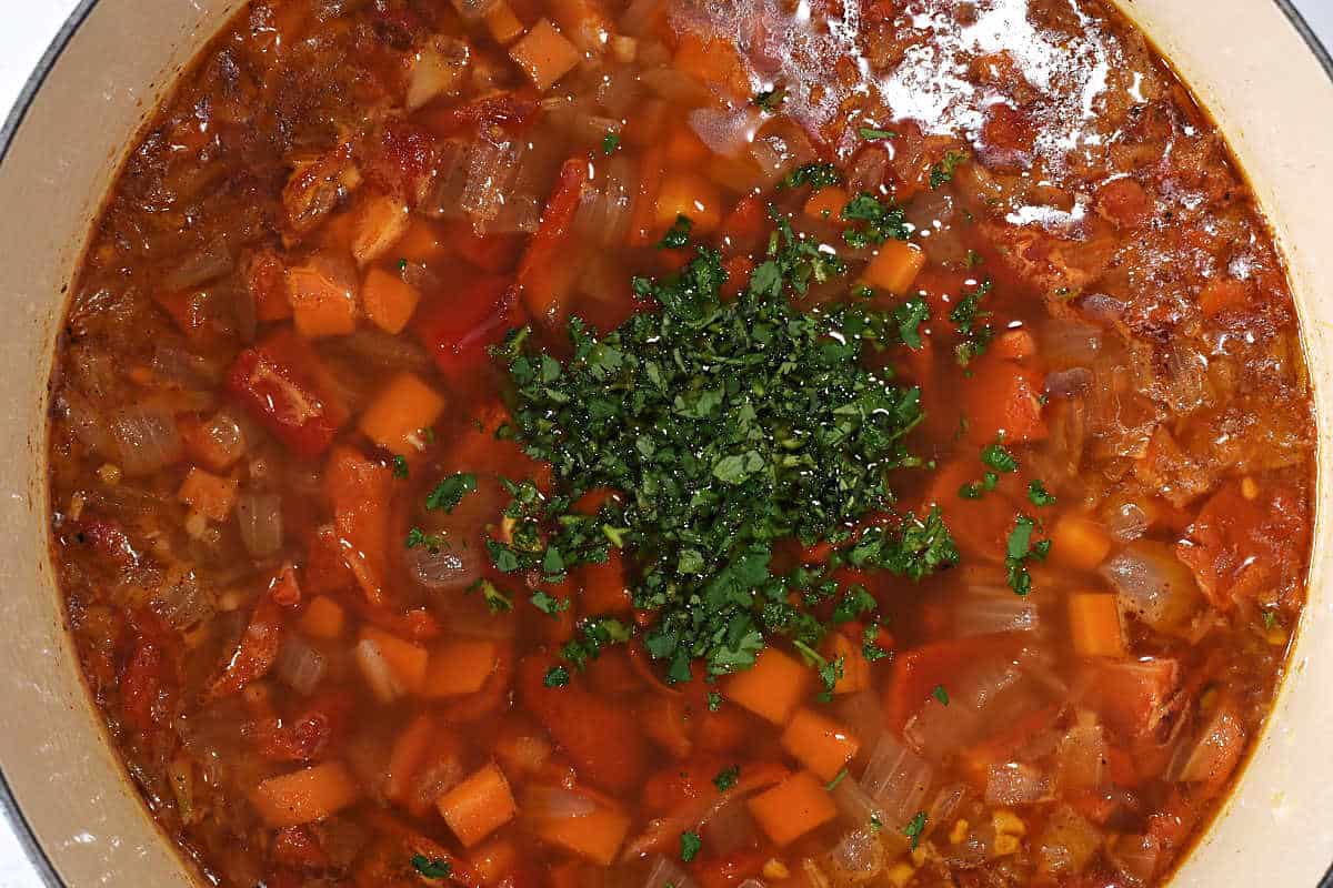 chopped-cilantro-on-top-of-cooked-roasted-red-pepper-soup-in-pot.