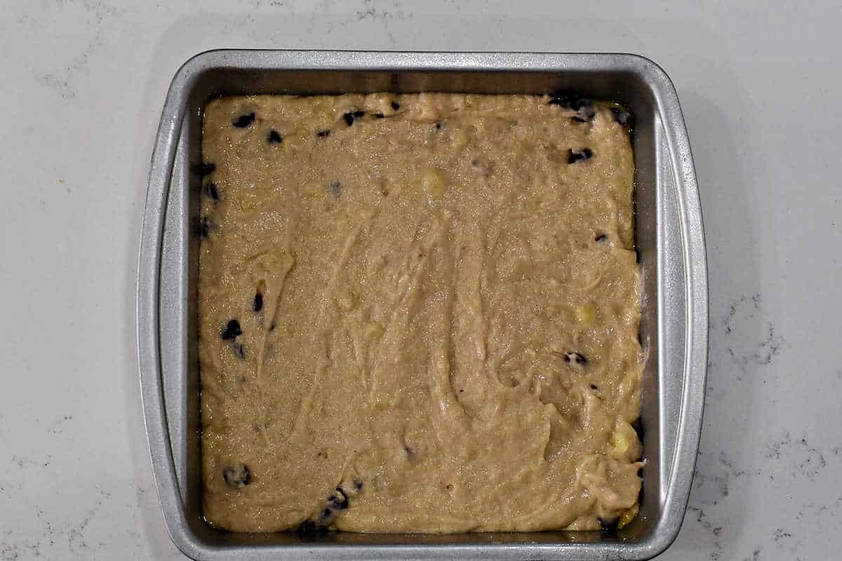 Banana chocolate chip cake mixture in a square baking pan.