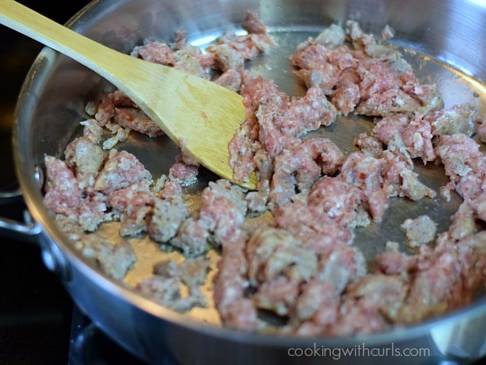 Breakfast sausage cooking in a large skillet.