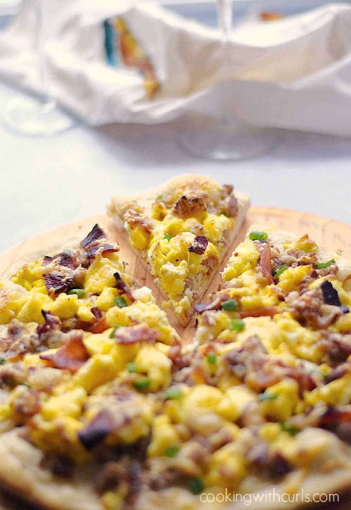 Breakfast Pizza with Sausage Gravy, bacon and scrambled eggs on a a wood pizza peel.