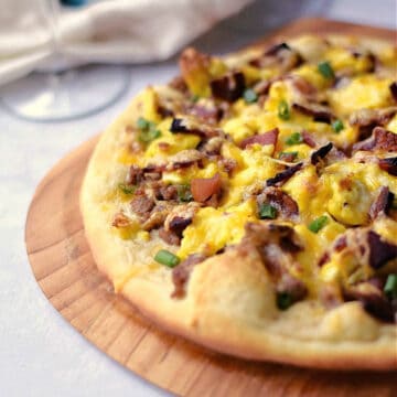 Breakfast Pizza with Sausage Gravy, scrambled eggs and bacon on a puffy pizza crust.