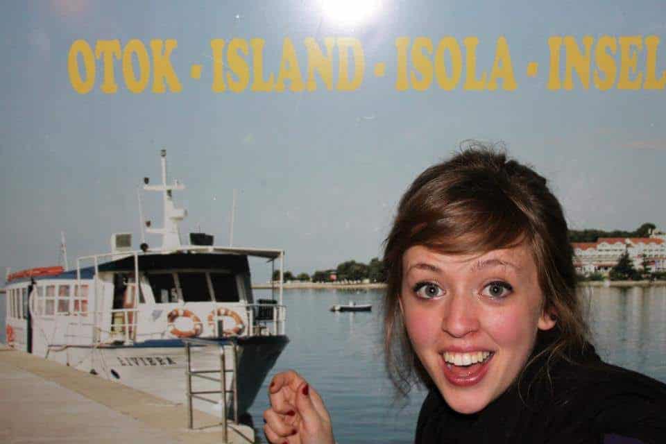 a girl smiling in front of a poster of a boat