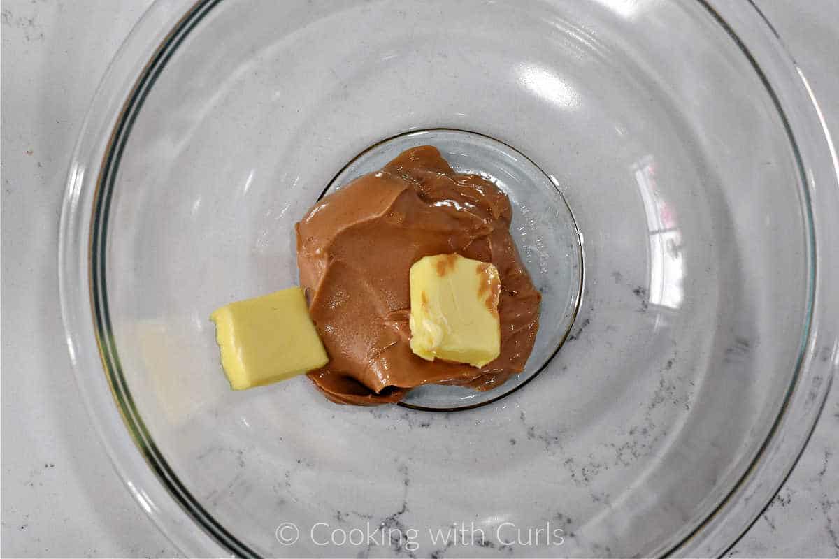 Peanut butter and two squares of butter in a mixing bowl.