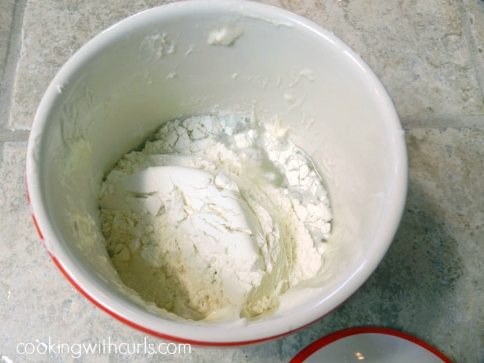 flour and water added to sourdough starter in a ceramic crock