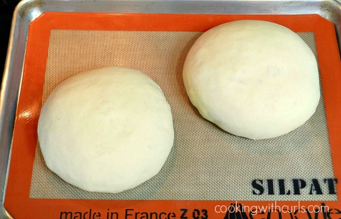 two balls of sourdough that have risen on a silcone lined baking sheet 