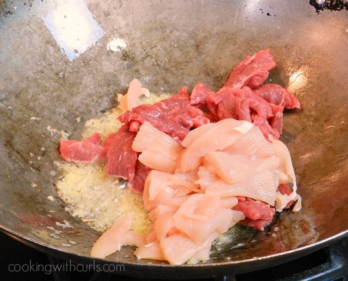 steak and chicken cooking in a wok with oil and ginger
