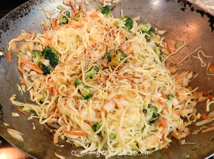 Wok with noodles, cabbage, vegetables and meat tossed together.