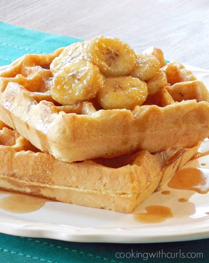 Two Belgian waffles on a plate topped with caramelized bananas.