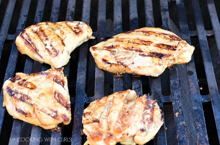 Four chicken breasts on the grill.