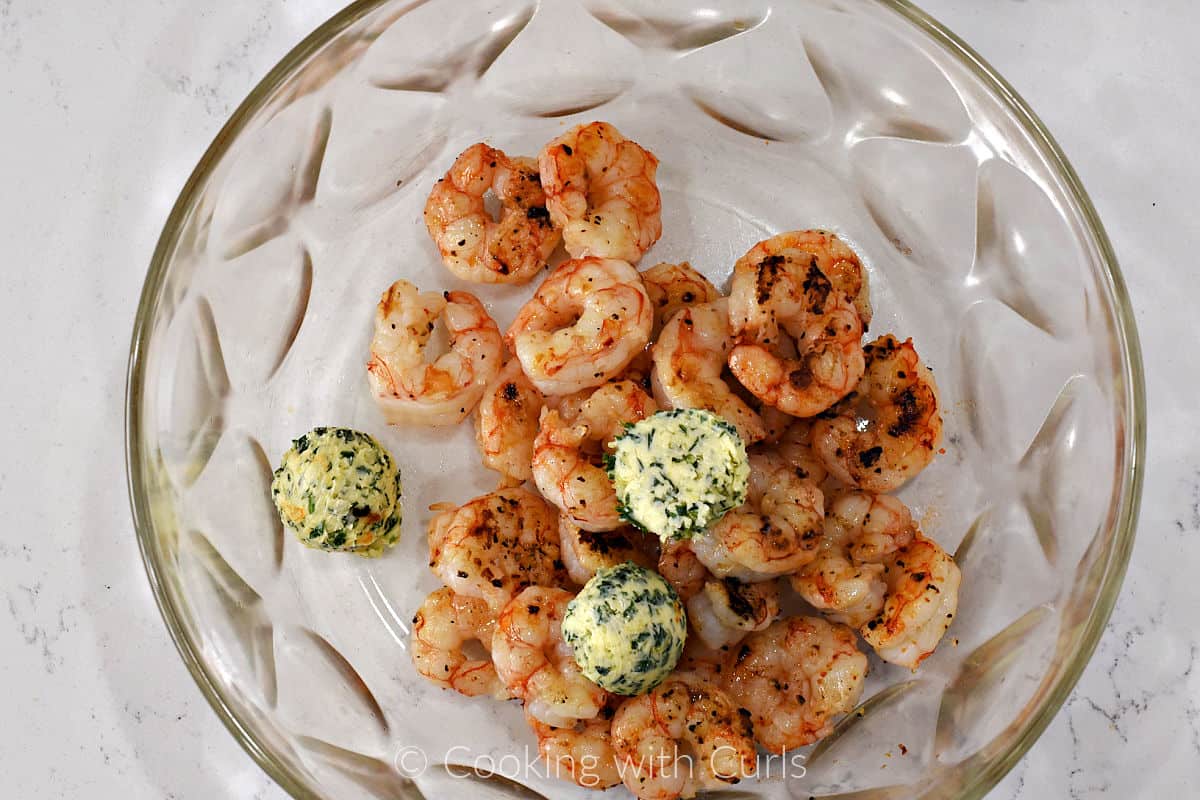 Grilled shrimp and three scoops of herb butter in a large bowl. 