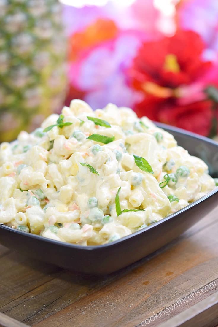 Traditional Hawaiian Potato Salad in a square serving bowl surrounded by tropical flowers.