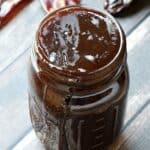 Cherry Chipotle Barbecue Sauce in a glass mason jar surrounded by dried chipotle peppers
